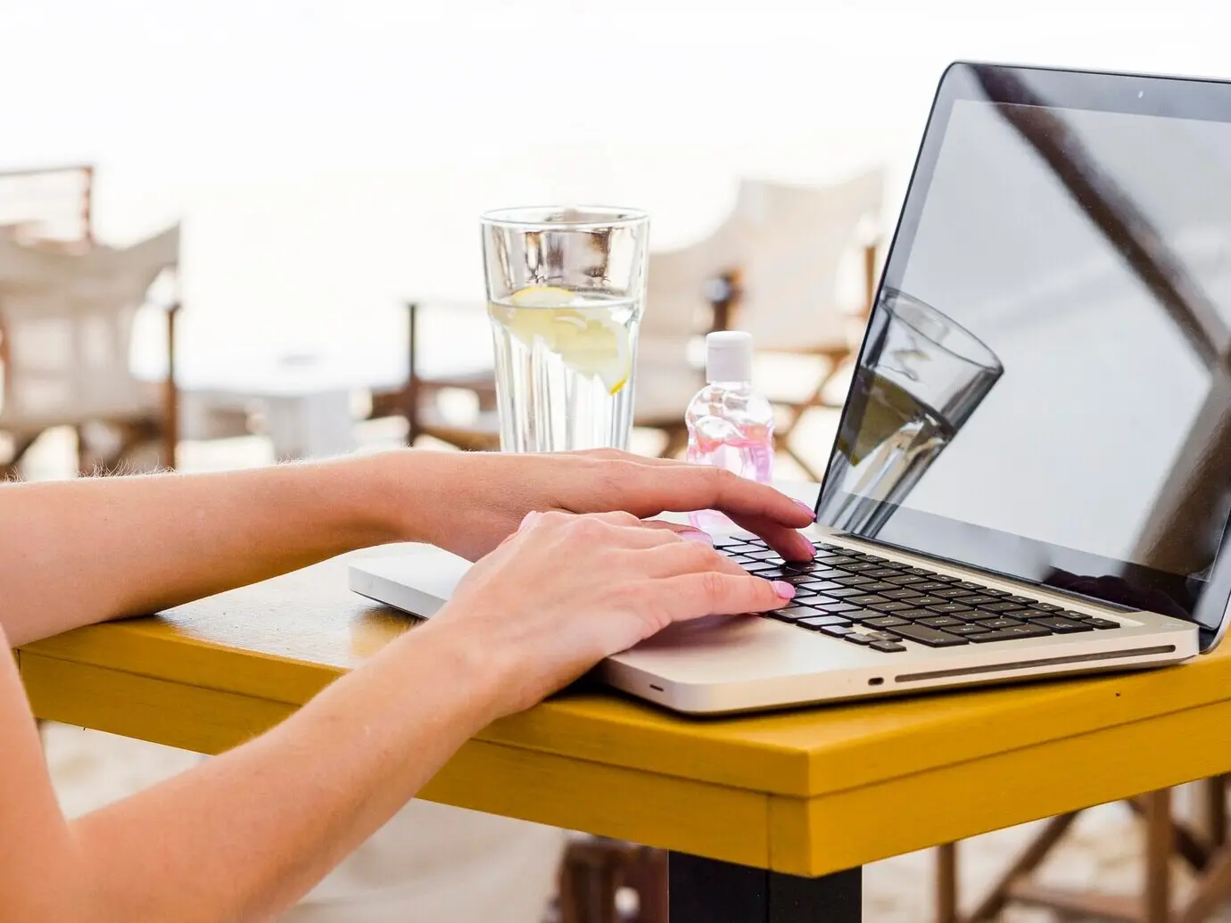 Ujęcie z boku kobiety pracującej na laptopie na zewnątrz.
